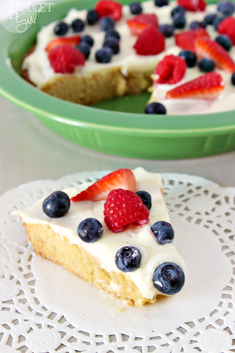 Sugar Cookie Cake --- A tender sugar cookie cake, filled with white chocolate chips, topped with cream cheese and fruit. A perfect dessert for the Fourth of July and other summer holiday parties. || via diybudgetgirl.com #sugar #cookie #cake #baking #summer #recipes #easy #fruit #creamcheese #topping #frosting #icing #cream #cheese 