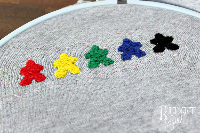 TableTop Day Embroidered Meeple Shirt --- Celebrate TableTop Day with this colorful, customizable embroidered meeple shirt!. Use the base game colors or colors of your choice. || via diybudgetgirl.com #tabletop #tabletopday #tshirt #shirt #meeples #embroider #embroidery #boardgames #games #gaming #crafts #diy